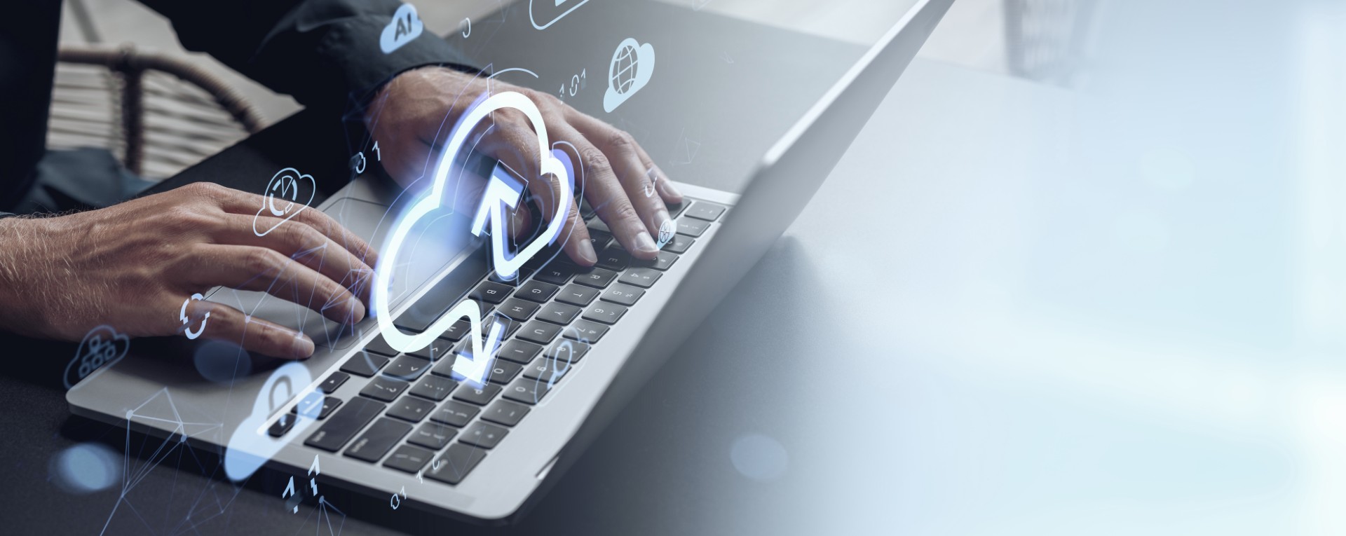 Das Bild zeigt die Arbeit an einem Laptop mit eingeblendeten Cloud-Symbolen für Upload, Download und digitale Vernetzung. Es veranschaulicht zentrale Themen wie Cloud-Speicher, Datensynchronisation, IT-Sicherheit und den effizienten Austausch von Informationen in modernen Cloud-Umgebungen.