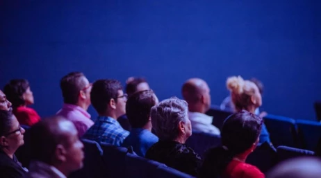 Audience members sit in rows and look attentively toward the front during an event or presentation.
