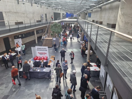 Das Bild zeigt den Empfangs- und Networkingbereich eines Fundraising-Kongresses mit Anmeldecounter, Infoständen und vielen Teilnehmenden im Austausch. Es steht für den 16. Fundraisingtag in München am 11. März 2027, bei dem Vereine und Stiftungen Impulse zu Spenden, Unternehmenskooperationen und Stiftungen erhalten. Die ISO-Gruppe ist mit Charity:up vor Ort und zeigt, wie personalisierte Videos Spenden oder Newsletter-Abos direkt im Video ermöglichen – ohne Medienbrüche.