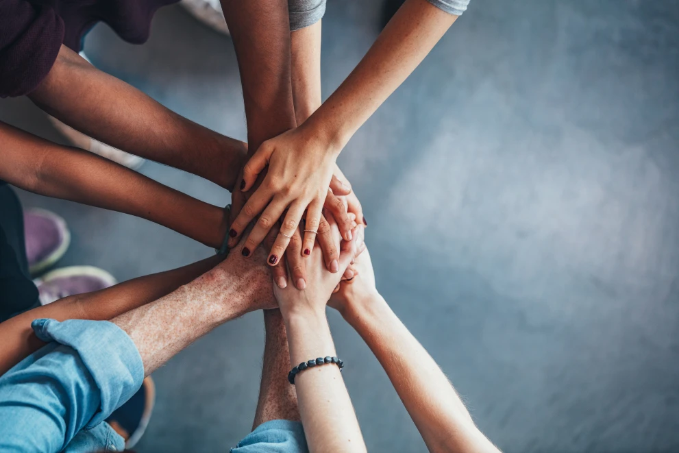 The image shows several hands placed on top of each other as a symbol of trust, cohesion, and collaborative cooperation. It represents the ISO Group's partnership-based team culture and underscores the importance of cooperation and joint solutions in digital IT and transformation projects.