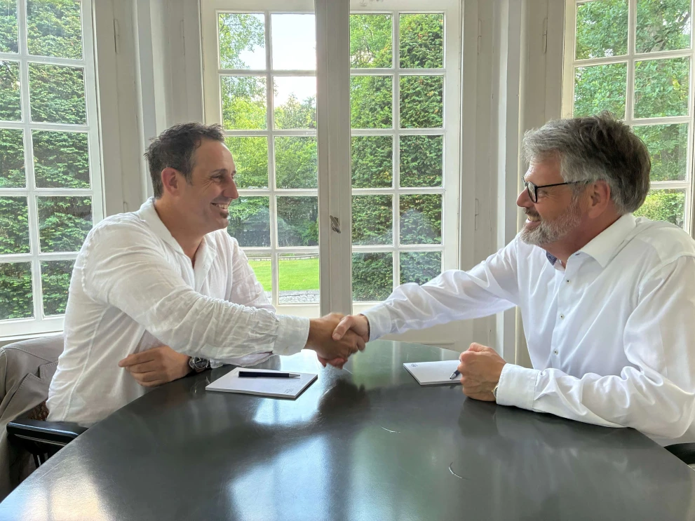 Representatives of ISO-Gruppe and Codesphere seal their collaboration with a handshake across a meeting table.
