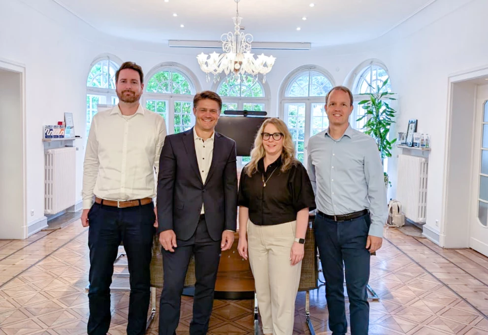 Das Bild zeigt vier Teammitglieder von Diamant Software und der ISO-Gruppe bei einem gemeinsamen Meeting. Die professionelle Atmosphäre und das helle Büro unterstreichen erfolgreiche Zusammenarbeit und Kompetenz im Bereich Digitalisierung und Finanzsoftware.