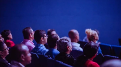 Audience members sit in rows and look attentively toward the front during an event or presentation.