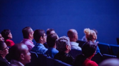 Audience members sit in rows and look attentively toward the front during an event or presentation.
