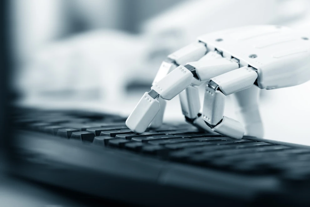 A robotic hand on a keyboard symbolizes AI-assisted programming and automated development tasks. It fits topics like coding assistants, AI pair programming, productivity gains, code review, and DevOps-adjacent workflows in enterprise software teams.