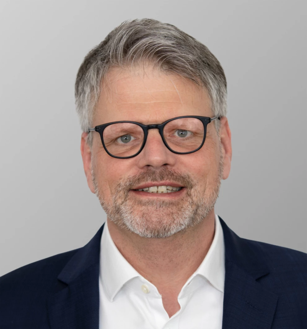 Porträtfoto von Johannes Reichel, Board-Mitglied der ISO-Gruppe, verantwortlich für Vertrieb und Marketing. Er trägt eine schwarze Brille, ein weißes Hemd und einen dunklen Anzug.

