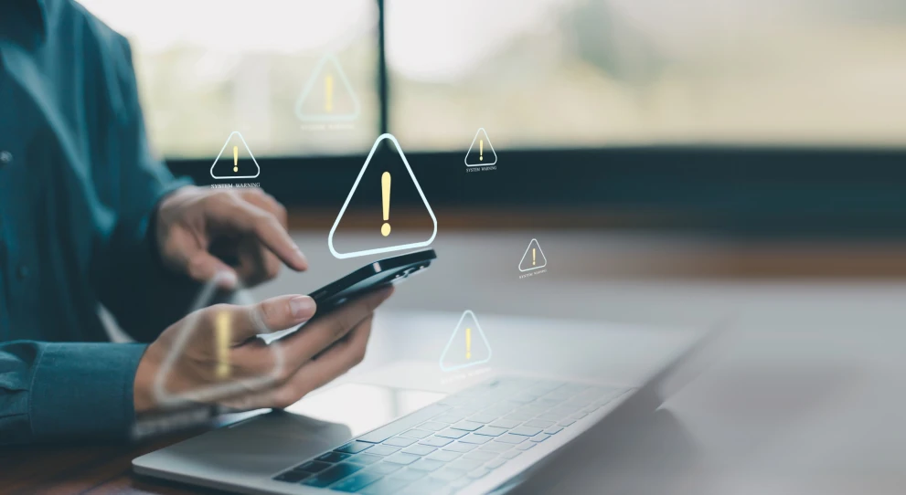 Warnsymbole über Smartphone und Laptop stehen für verdächtige Aktivitäten und automatisierte Alerts in digitalen Prozessen. Das Motiv passt zu Fraud Detection, Anomaly Detection, Transaktionsmonitoring, Risk Scoring und Prävention von Betrug im Finance- und E‑Commerce-Umfeld.